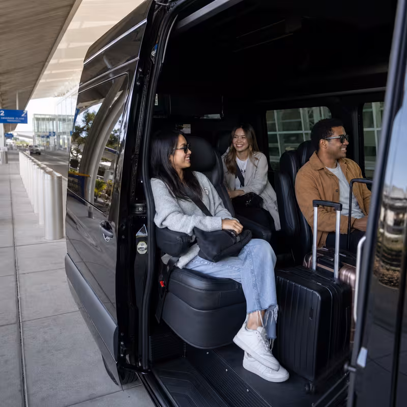 Passengers loading luggage while boarding an Oakland group shuttle