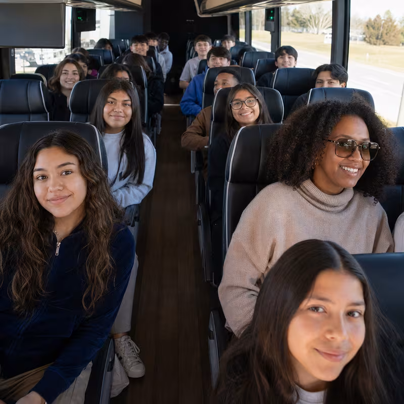 Group boarding a white charter bus for School Transportation transportation in Oakland